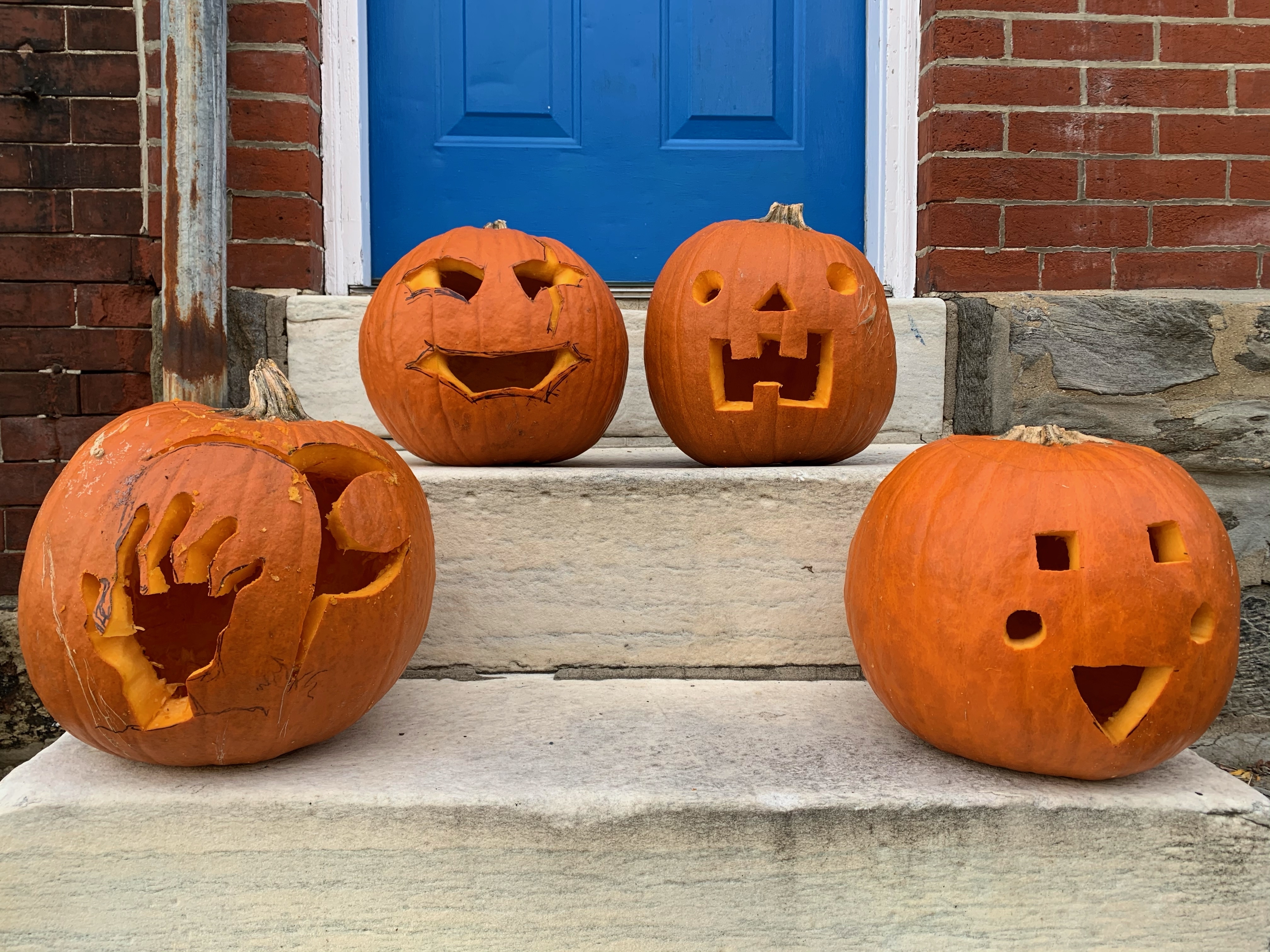 Four of the carved pumpkins sitting on a stoop