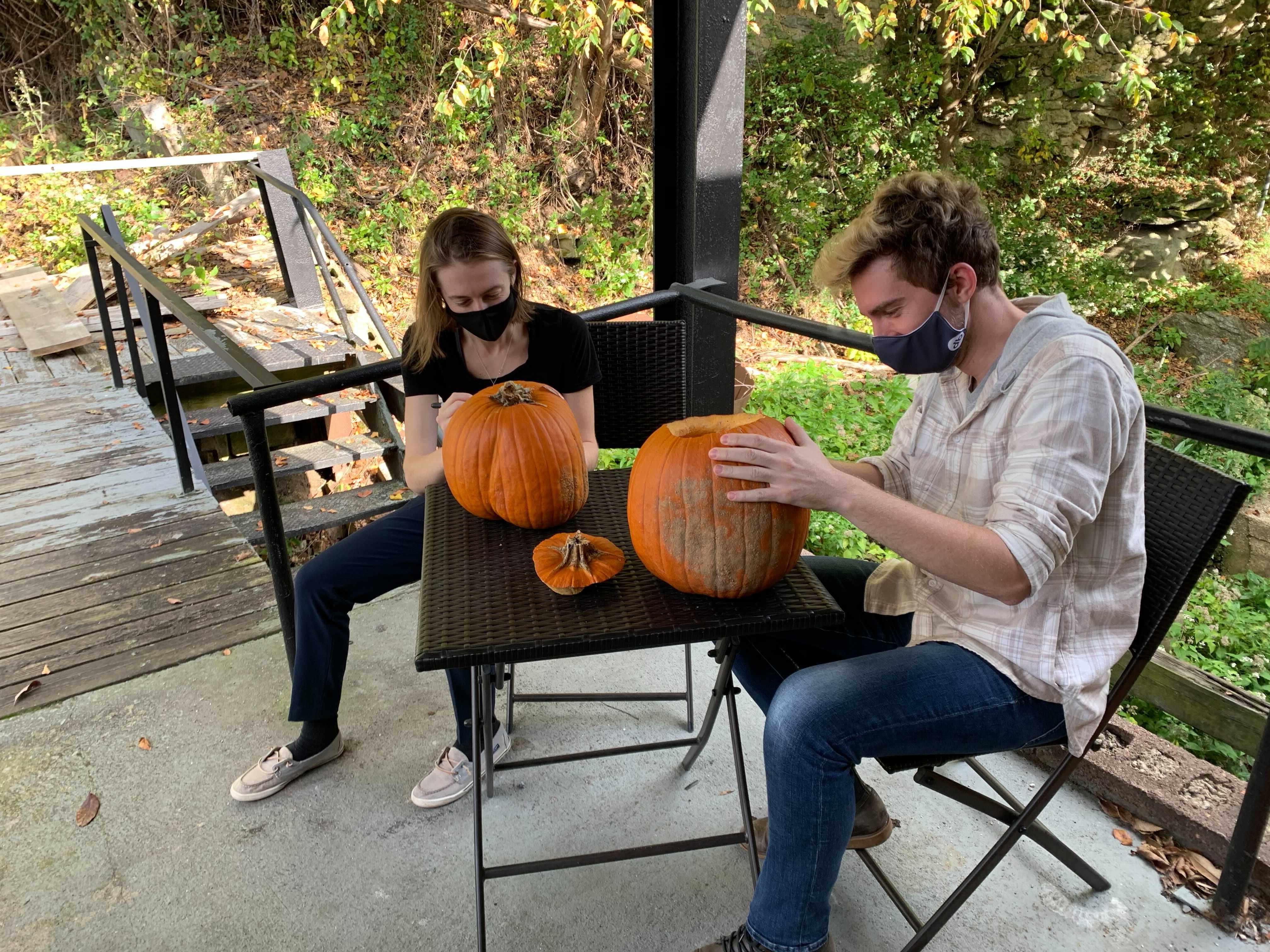 Two members of the visualization team sitting at a table to carve pumpkins