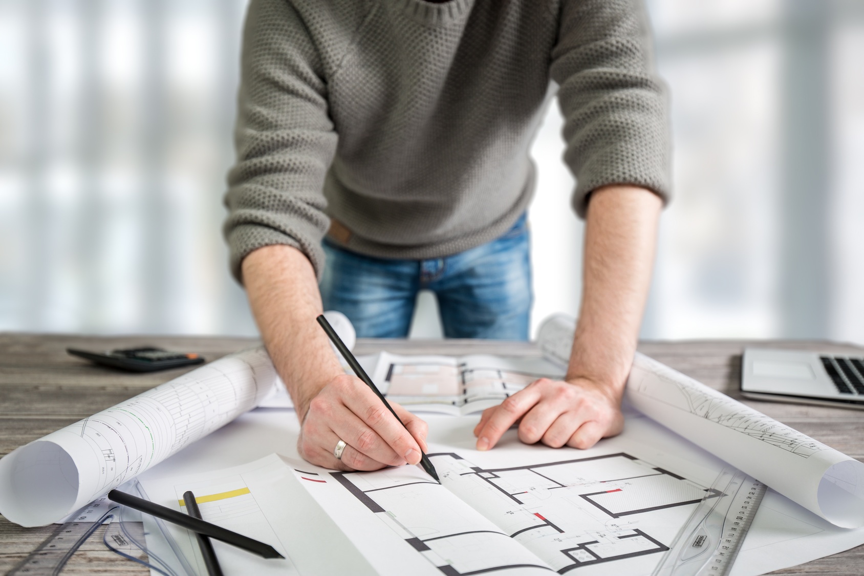 A man leaning over a set of architectural drawings
