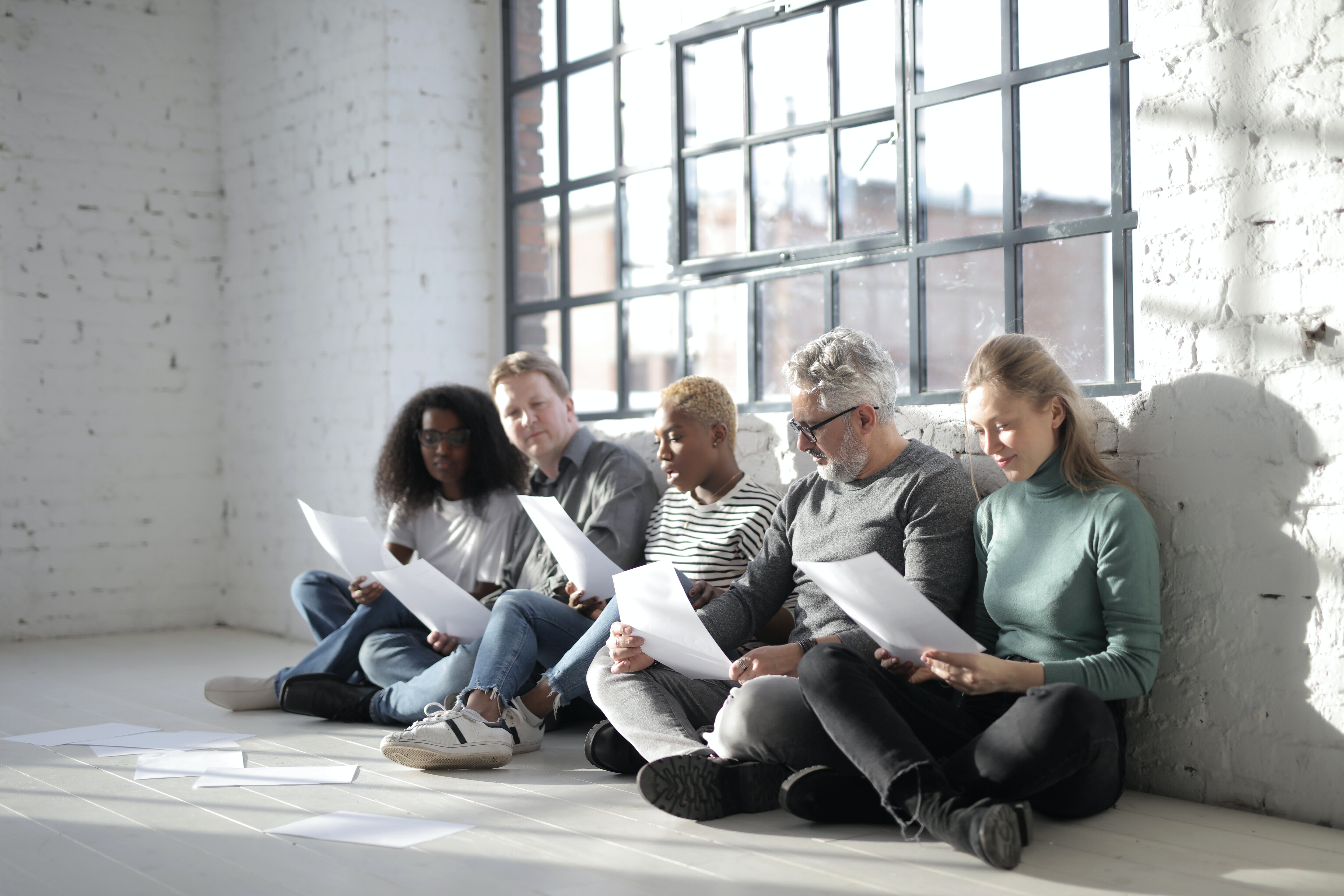A team of five people sit on floor to discuss plans together